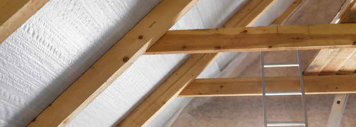 Loft insulation installed between roof beams to improve home energy efficiency