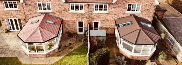 Two adjoining brick homes with SupaLite tiled conservatory roofs and skylights, showcasing energy-efficient and stylish home extensions.